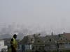 A worker cleans grass at Alamo Square Park as smoke from wildfires and fog obscures the skyline above the “Painted Ladies,” a row of historical Victorian homes, in San Francisco.