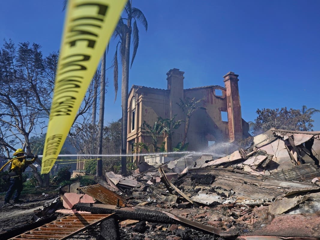 A firefighter hoses down hot spots from a home in the aftermath of the Coastal Fire Thursday, May 12, 2022, in Laguna Niguel, Calif. 