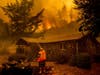 Jerry Kuny sprays water on a home as flames from the LNU Lightning Complex fires approach, Tuesday, Aug. 18, 2020, in unincorporated Napa County, Calif. 