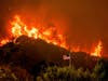 A flag flies as flames from the LNU Lightning Complex fires crest a ridge Tuesday, Aug. 18, 2020, in Napa County, Calif. The blaze went on to destroy multiple homes near Lake Berryessa