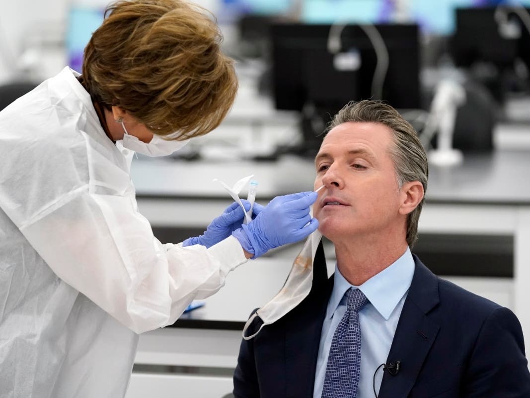Dr. Haleh Farzanmehr, left, administers a COVID-19 test to California Gov. Gavin Newsom at a new testing facility Friday, Oct. 30, 2020, in Valencia, California.