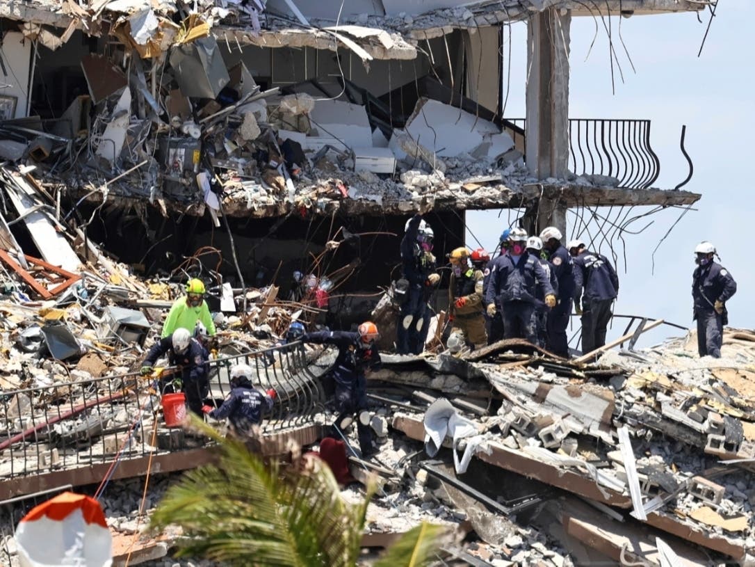 Search and rescue personnel look for survivors through the rubble at the Champlain Towers South in Surfside, Fla. At least 10 people have died and more than 150 remain missing. 
