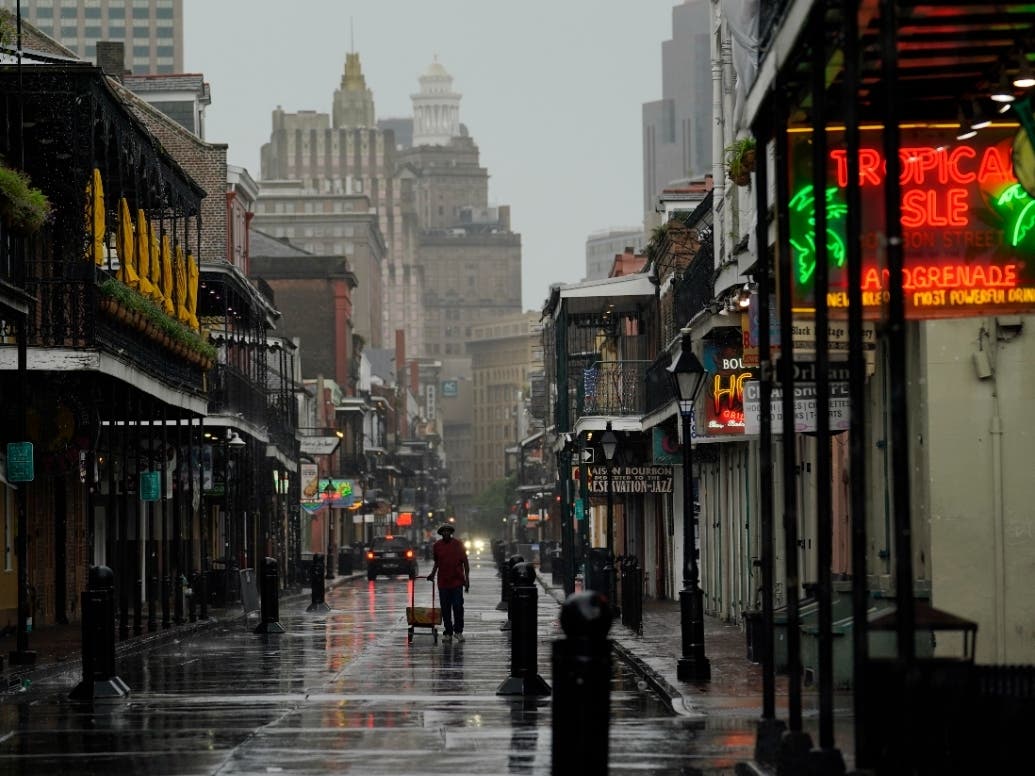 A man pulls a cart down a mostly deserted Bourbon Street in the French Quarter as the early effects of Hurricane Ida are felt on Sunday.