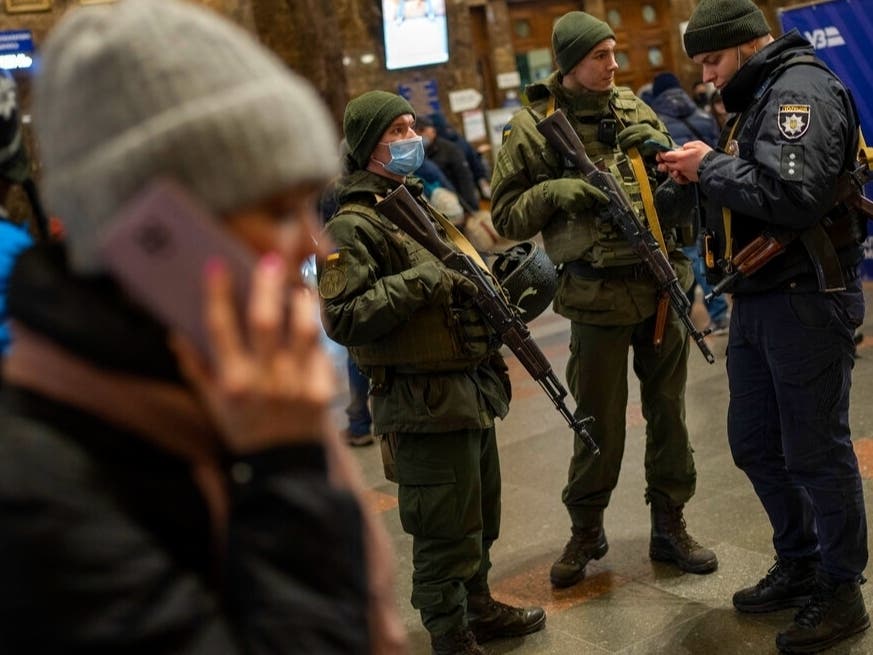Ukrainian soldiers stand guard as people try to leave at the Kyiv train station, Ukraine, Thursday, Feb. 24, 2022.