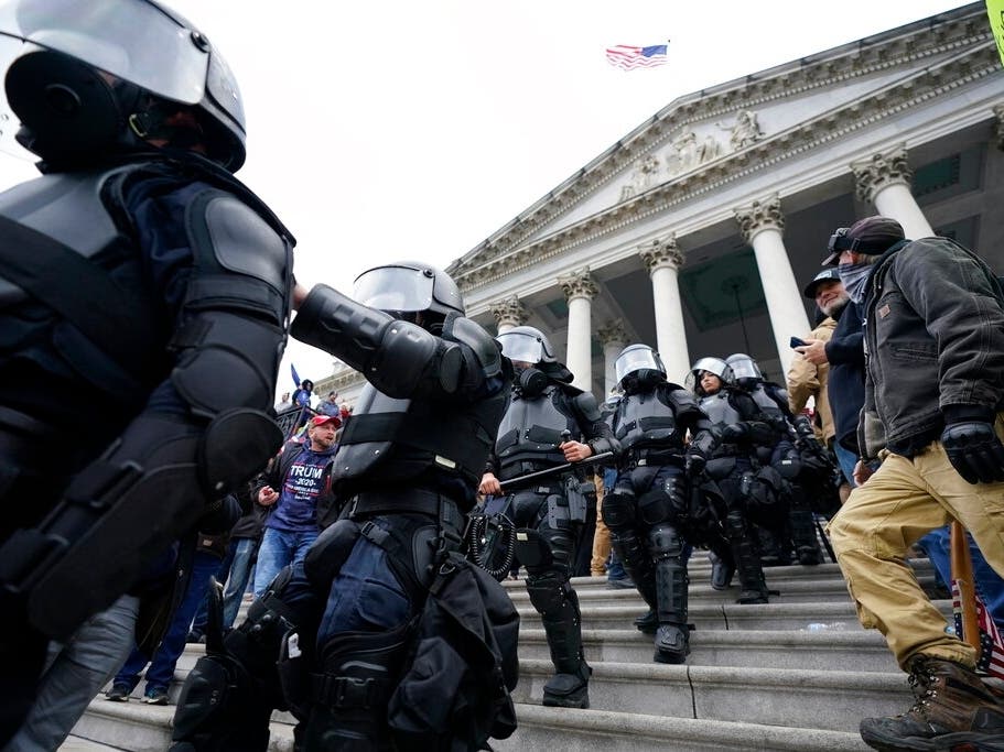 Police in riot gear walk out of the Capitol building Wednesday afternoon, after protesters stormed the building.