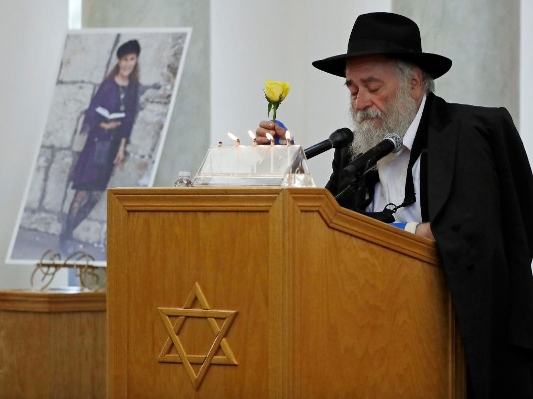 Yisroel Goldstein, Rabbi of Chabad of Poway, holds a yellow rose as he speaks at the funeral for Lori Kaye, who is pictured at left, in Poway, Calif. Prosecutors say John T. Earnest opened fire during the Passover service at the synagogue on April 27.