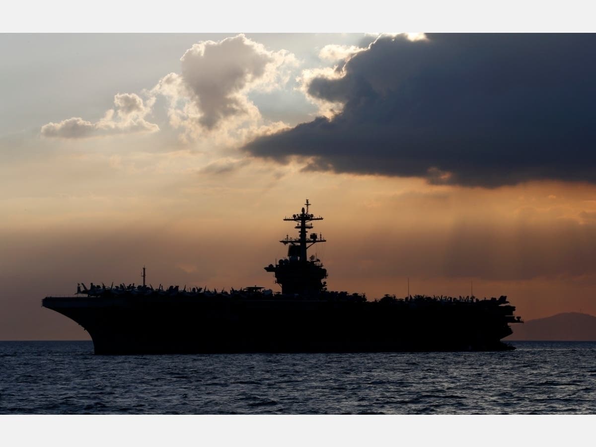 In this April 13, 2018, file photo the USS Theodore Roosevelt aircraft carrier is anchored off Manila Bay west of Manila, Philippines. 