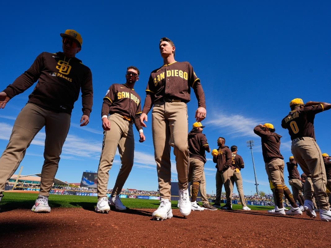 San Diego Padres team members walk back to the dugout after standing for the national anthem before a spring training baseball game against the Seattle Mariners, Friday, Feb. 20, 2026, in Peoria, Ariz.