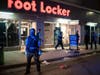 Minneapolis police stand outside a looted Foot Locker store on South 7th Street on Wednesday in Minneapolis. The Minneapolis mayor imposed a curfew Wednesday night and requested National Guard help after unrest broke out downtown.