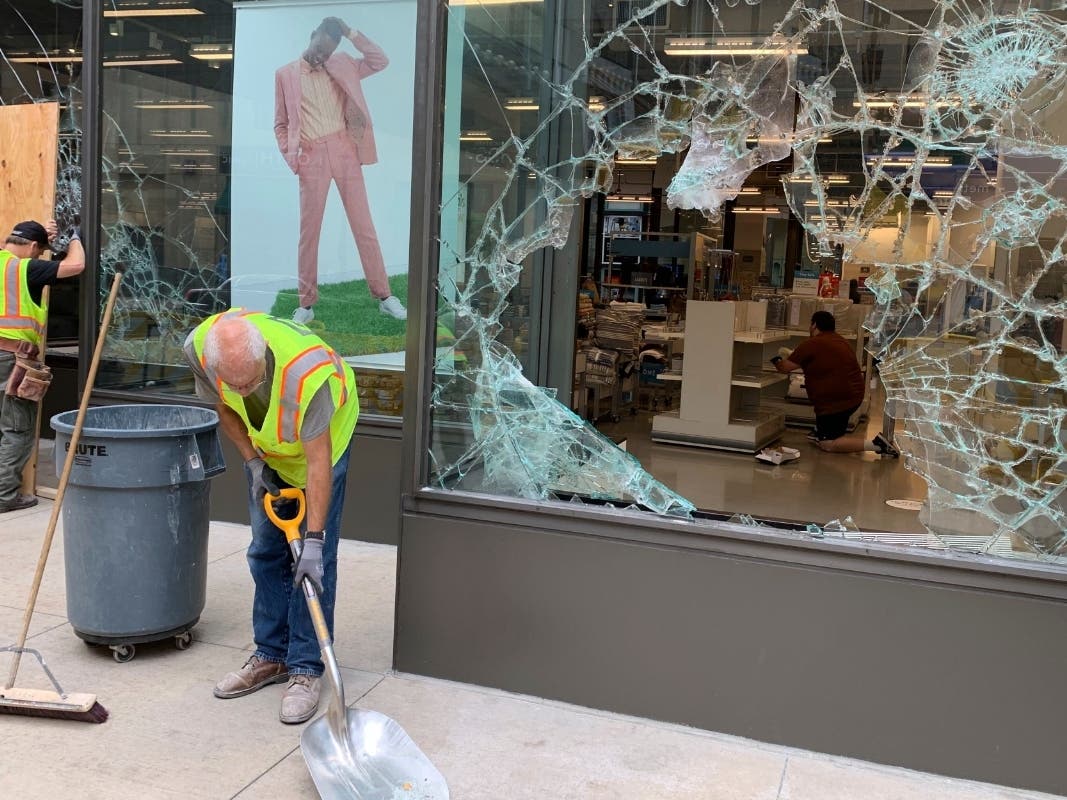 A worker shovels broken glass outside of Nordstrom Rack in downtown Minneapolis on Thursday, Aug. 27, 2020.