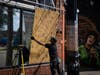 A man boards up a broken window to a barber shop after shots were fired in George Floyd Square on the one year anniversary of George Floyd's death on Tuesday, May 25, 2021, in Minneapolis.