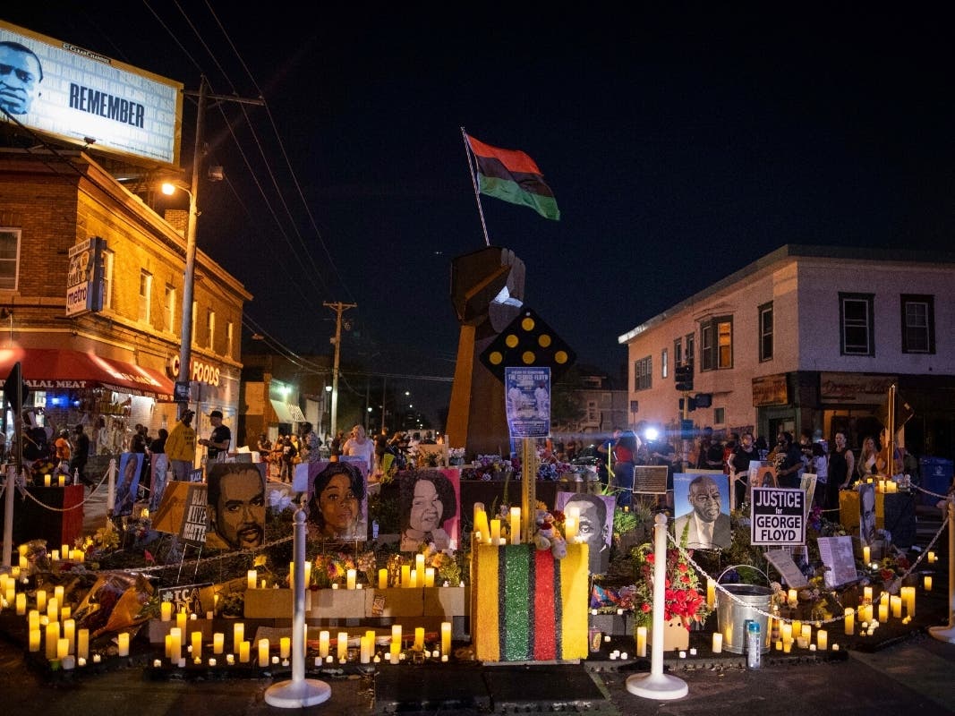 Community members place candles around the iron fist at 38th Street and Chicago Avenue, informally known as George Floyd Square, on the one-year anniversary of George Floyd's death, Tuesday, May 25, 2021, in Minneapolis.