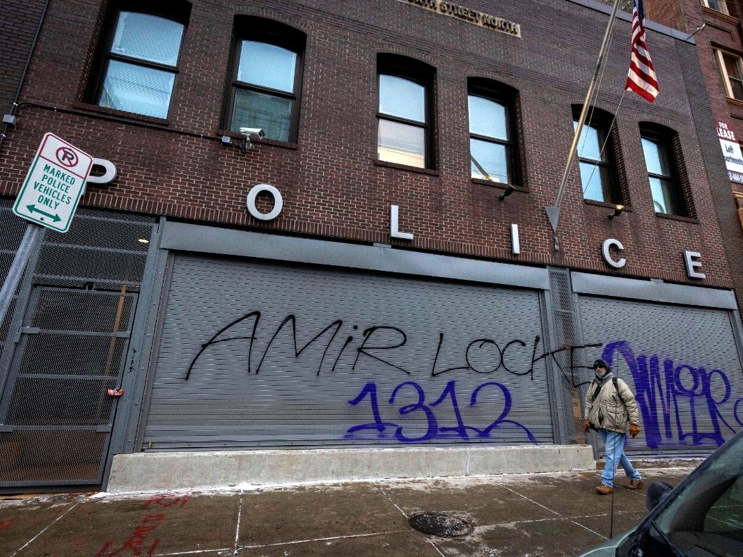 Protesters spray paint Amir Locke's name on the exterior shutter of a police precinct during a rally on Saturday, Feb. 5, 2022, in Minneapolis.