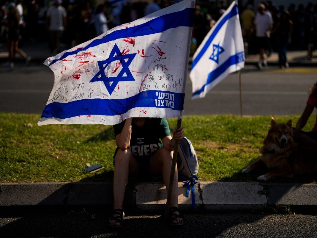 A woman grabs an Israeli flag stained with red paint during a protest demanding the release of dozens of Israelis who have been abducted during last week's unprecedented Hamas attack, in Tel Aviv, Israel, Saturday, Oct. 14, 2023.