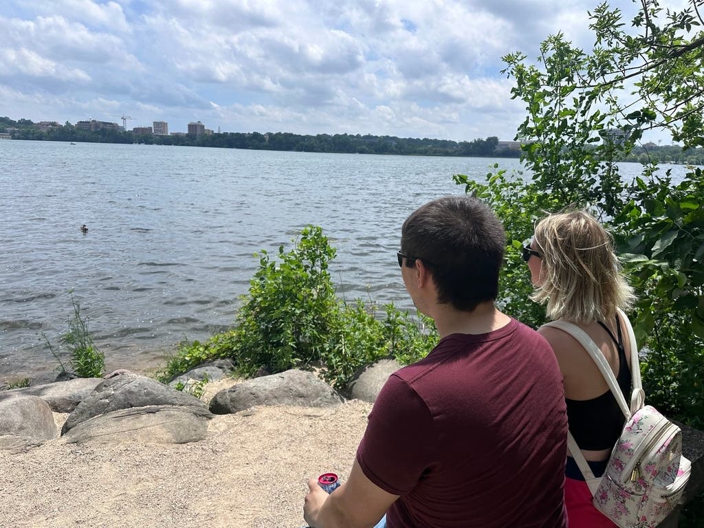 Toni Kreutzer, left, and Travis Rogne, right, take a break from the heat and sit on a bench along the shores of Lake Mendota in Madison, Wis., on Monday, June 29, 2026.