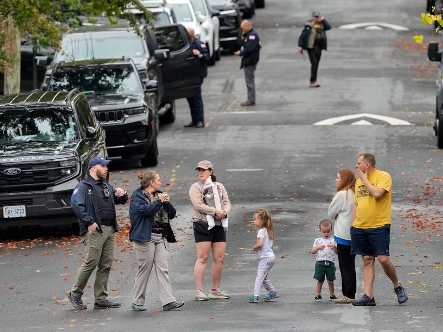Homeland Security officers speak with local residents on 26th Street NE in Washington, early Monday, Oct. 12, 2026, during an investigation at the residence of Rep. Ilhan Omar, D-Minn.