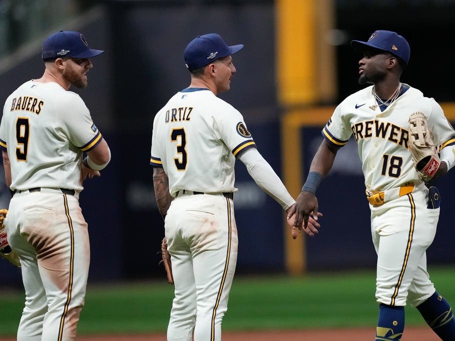 Milwaukee Brewers right fielder Luis Lara (18) celebrates with shortstop Joey Ortiz (3) and first baseman Jake Bauers (9) after Game 1 of baseball's National League Championship Series between the Milwaukee Brewers and the Los Angeles Dodgers, Sunday.