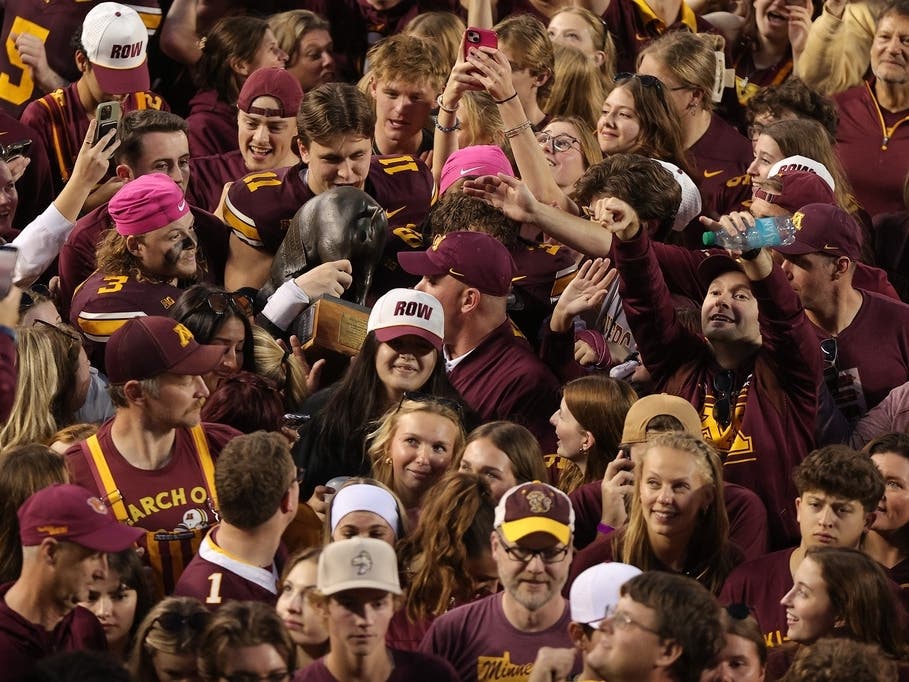 Minnesota fans celebrates around the Floyd of Rosedale trophy after an NCAA college football game against Iowa, Saturday, Oct. 24, 2026, in Minneapolis.