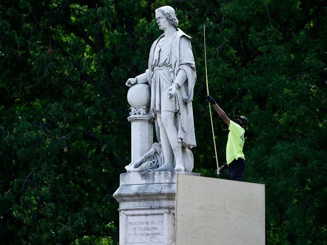 A city worker measures the statue of Christopher Columbus at Marconi Plaza as they build a cover, Tuesday, June 16, 2020, in the South Philadelphia neighborhood of Philadelphia.