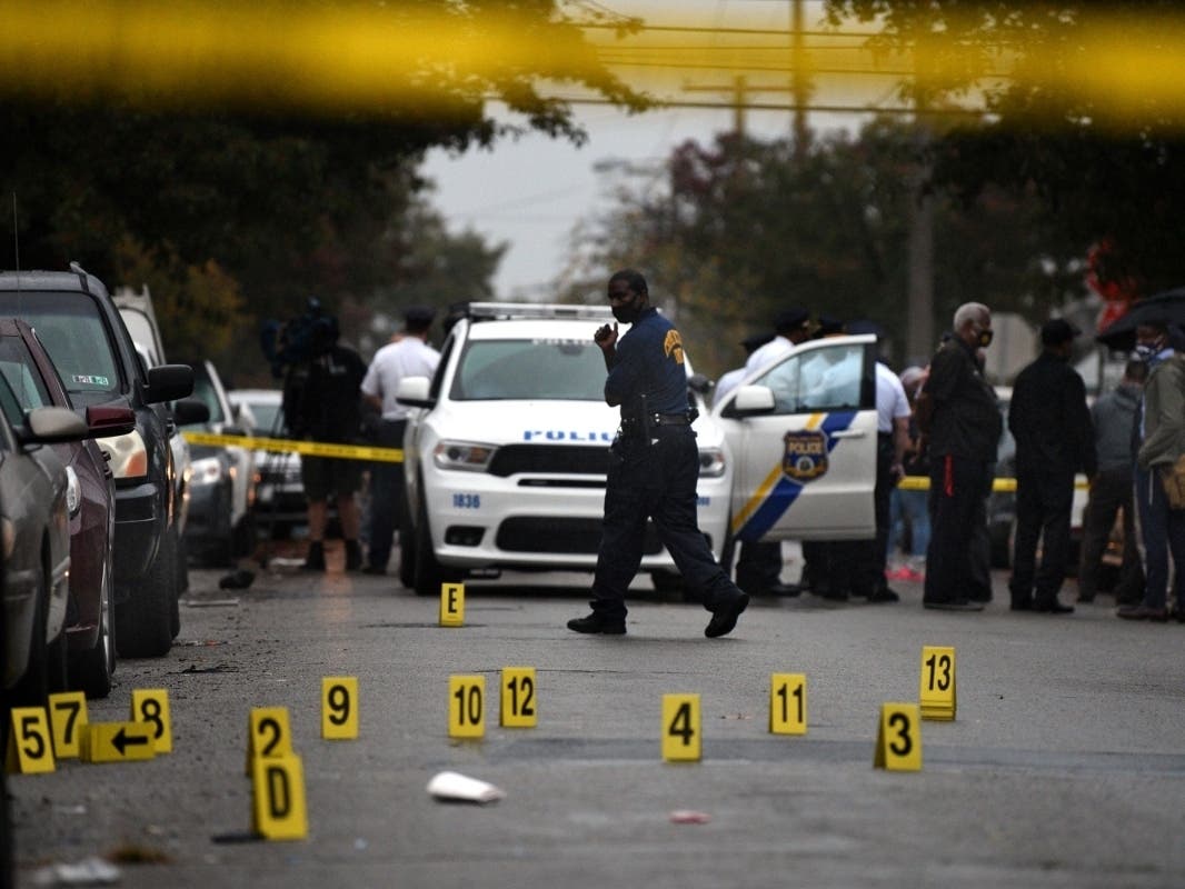 People stand near the scene of a police shooting in Philadelphia, Monday, Oct. 26, 2020, after police officers fatally shot a man during a confrontation.