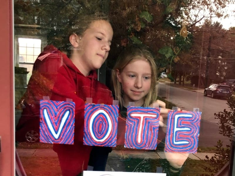 Sisters Maya and Julia Schmitt tape homemade signs on their home's front storm door on Election Day Tuesday Nov. 3, 2020, in the Philadelphia suburb of Havertown, Pa.