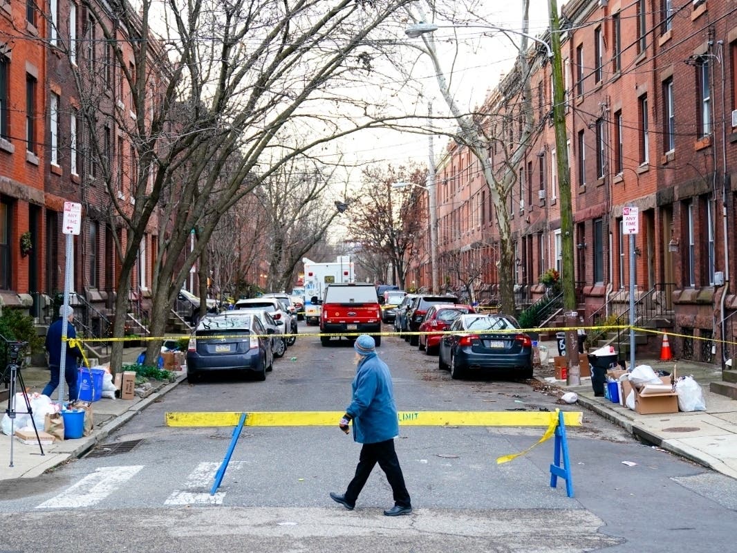 Cause undetermined in Philadelphia house fire that killed 12 A passer-by looks over the barricade on the street of Wednesday's deadly fire in the Fairmount neighborhood of Philadelphia on Thursday, Jan. 6, 2022.
