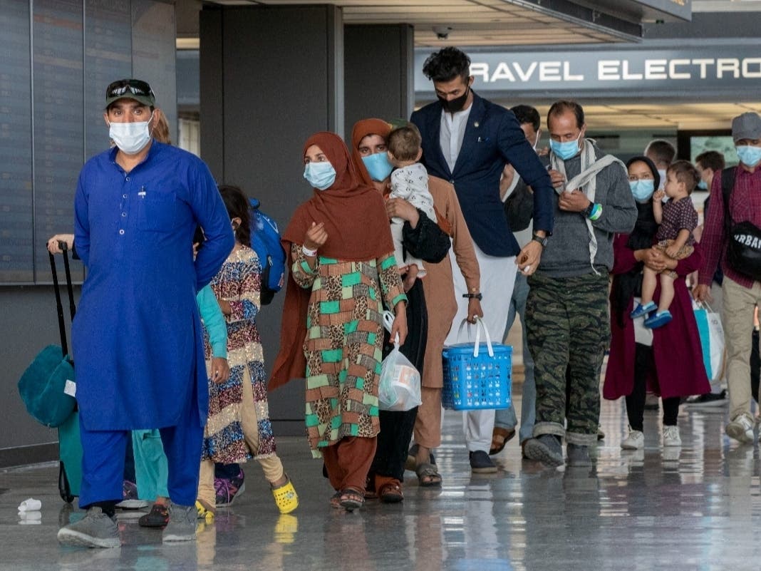In this Tuesday, Aug. 31, 2021, file photo, families evacuated from Kabul, Afghanistan, walk through the terminal to board a bus after they arrived at Washington Dulles International Airport, in Chantilly, Va.