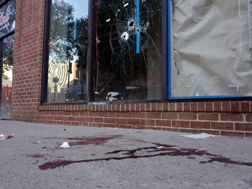Blood is seen at the scene of a fatal overnight shooting on South Street in Philadelphia, Sunday, June 5, 2022, where bullet holes on a storefront window from a prior shooting can also be seen.