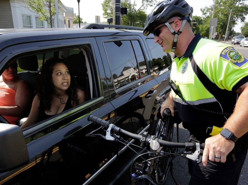 n this July 20, 2016 photo, police officer Matthew Monteiro speaks to a motorist about texting while driving while patrolling on his bicycle in West Bridgewater.