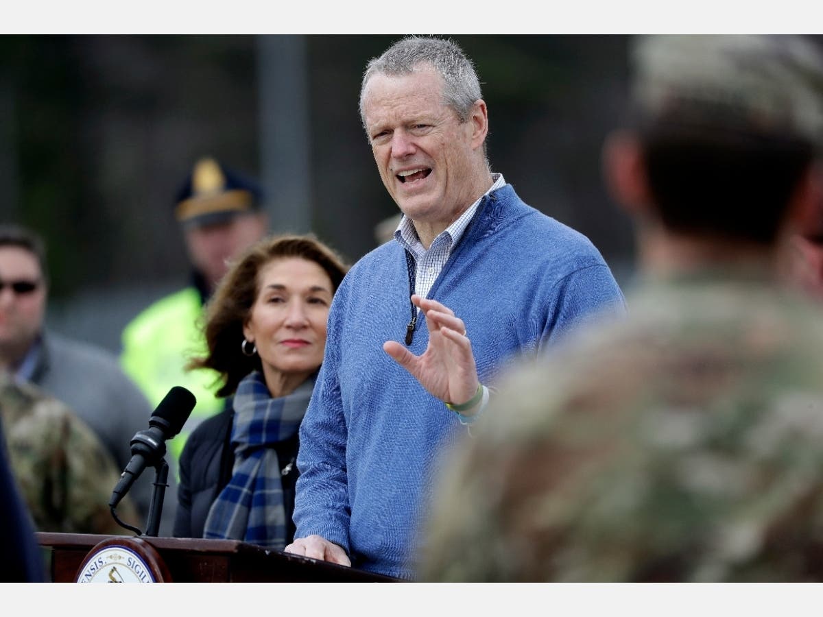 Gov. Charlie Baker speaks on Sunday at a coronavirus testing site set up at Gillette Stadium as Lt. Gov. Karyn Polito looks on.