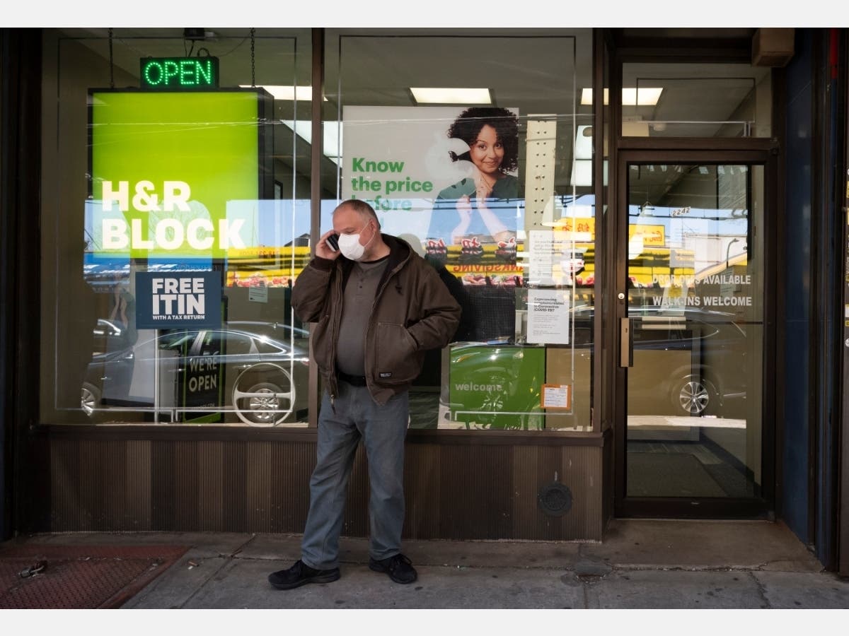 A man wearing a mask waits outside a H&R Block tax preparation office for an appointment during the coronavirus pandemic on April 6 in Brooklyn, New York. 
