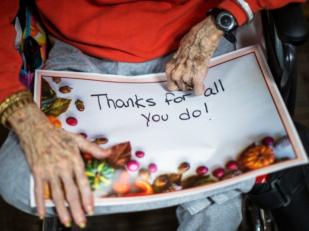 A nursing home resident holds a sign addressed to the staff before a small Thanksgiving Day parade with nurses, other staff and residents at the Hebrew home at Riverdale in the Bronx.