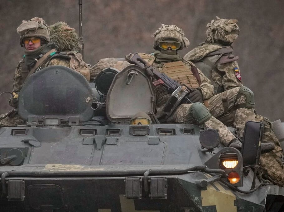 Ukrainian servicemen sit atop armored personnel carriers on a road in the Donetsk region, eastern Ukraine, on Thursday.