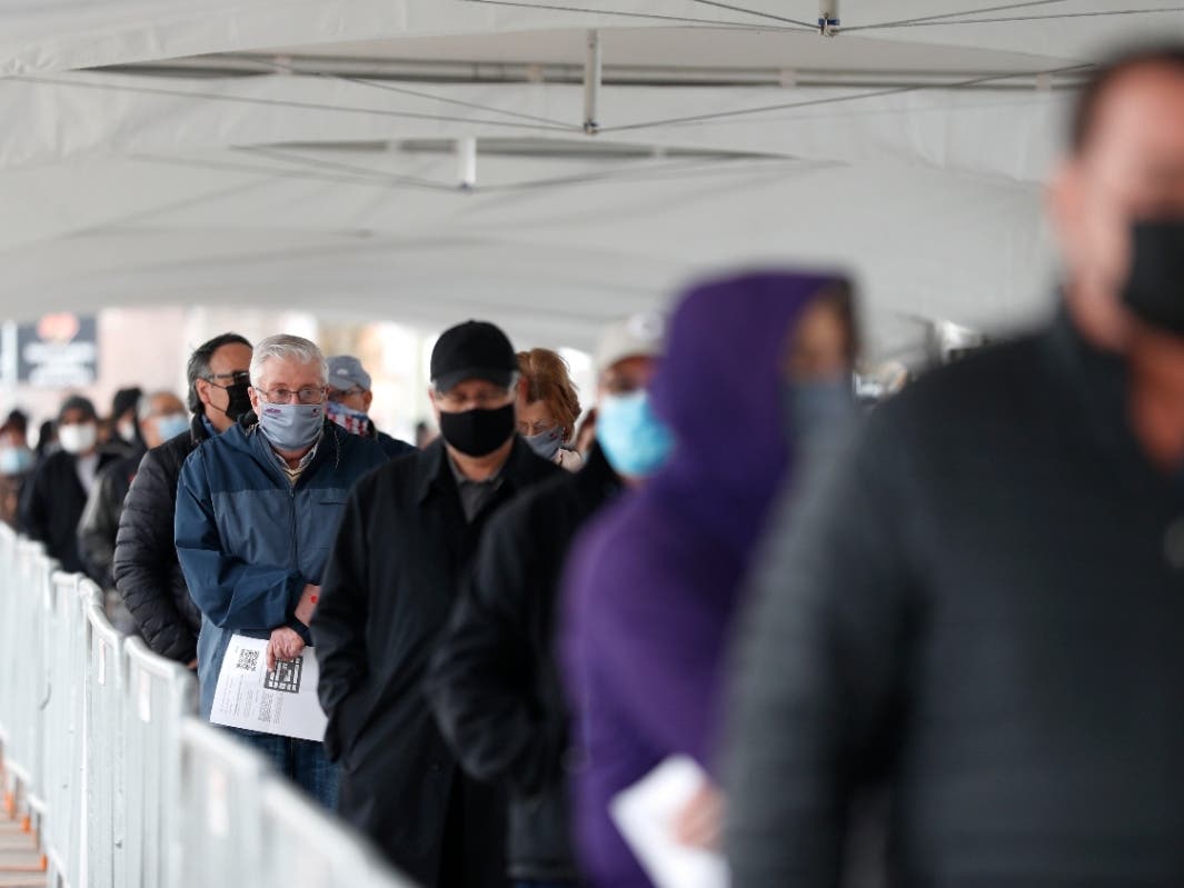 People wait in line at a check-in area to enter a mass COVID-19 vaccination site March 10 at the United Center in Chicago
