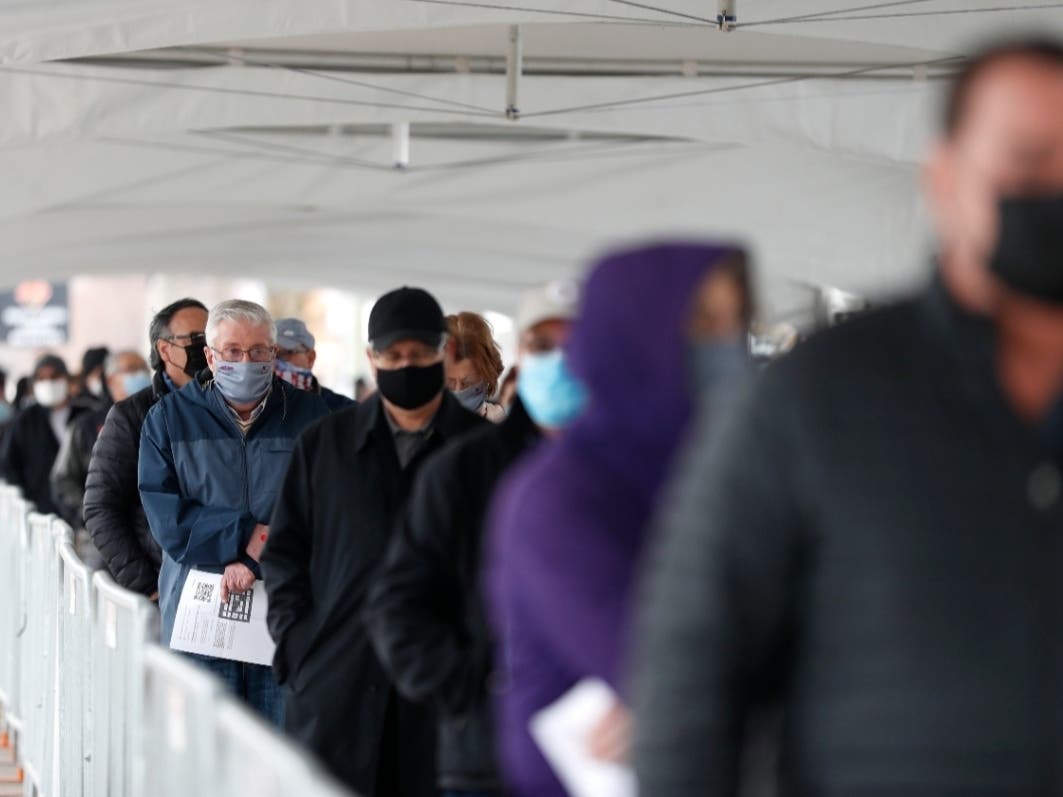 People wait in line at a check-in area to enter a mass COVID-19 vaccination site March 10 at the United Center in Chicago.