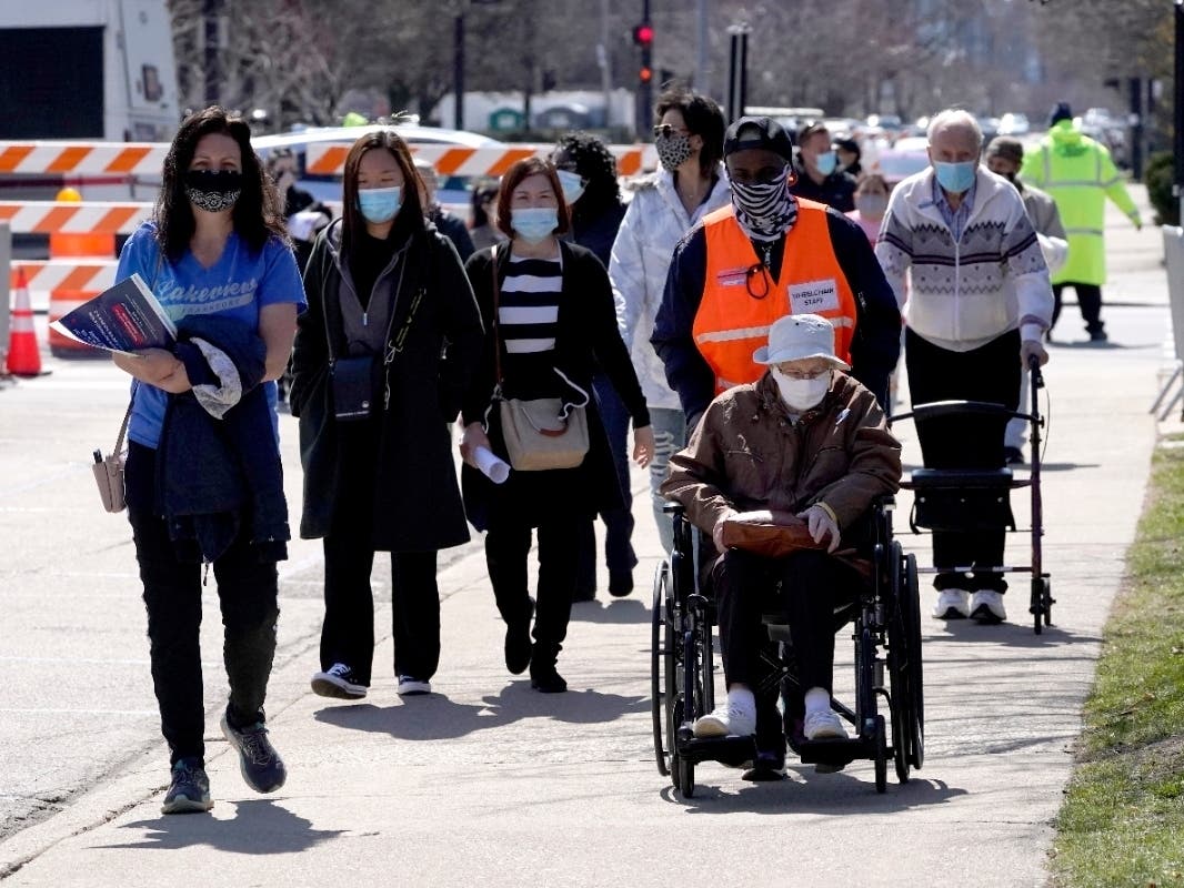 Residents pass between the drive-thru and walk-in areas of the United Center mass vaccination site Monday. State and local officials announce three new suburban COVID-19 vaccination sites.