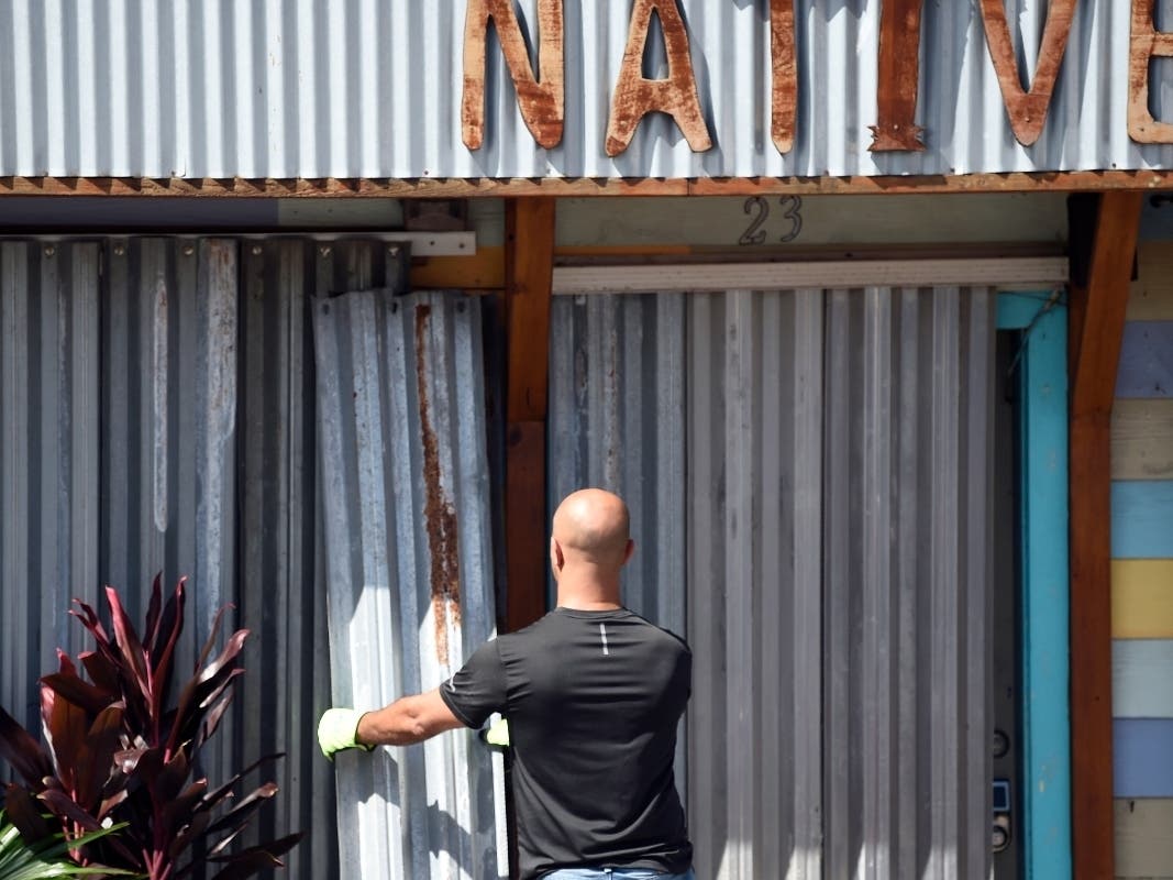 A worker affixes corrugated metal to the front of a business along the main drag in Folly Beach, S.C., on Tuesday, Sept. 3, 2019. 