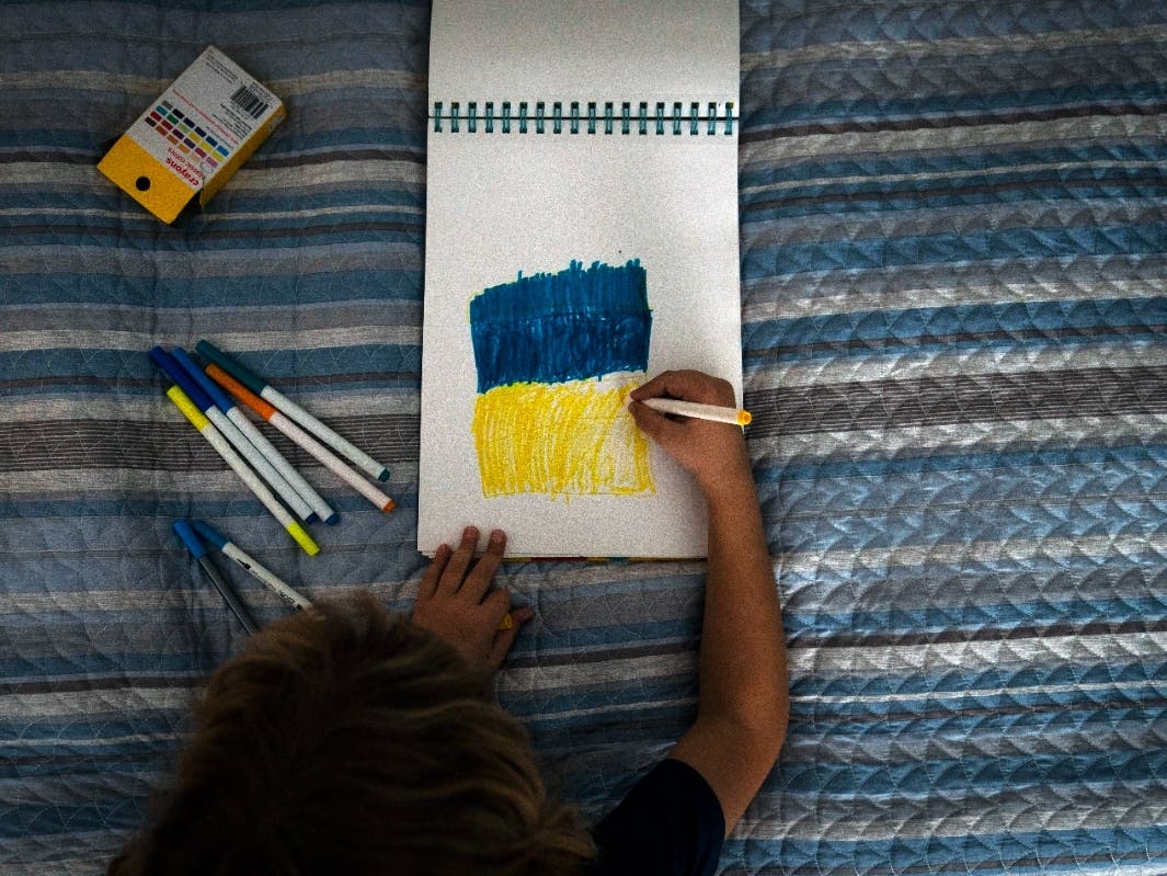 Hanna Tverdokhlib's 7-year-old son, Volodymyr, draws a Ukrainian flag in a living room of their apartment in Long Beach, Calif., Tuesday, March 1, 2022. 