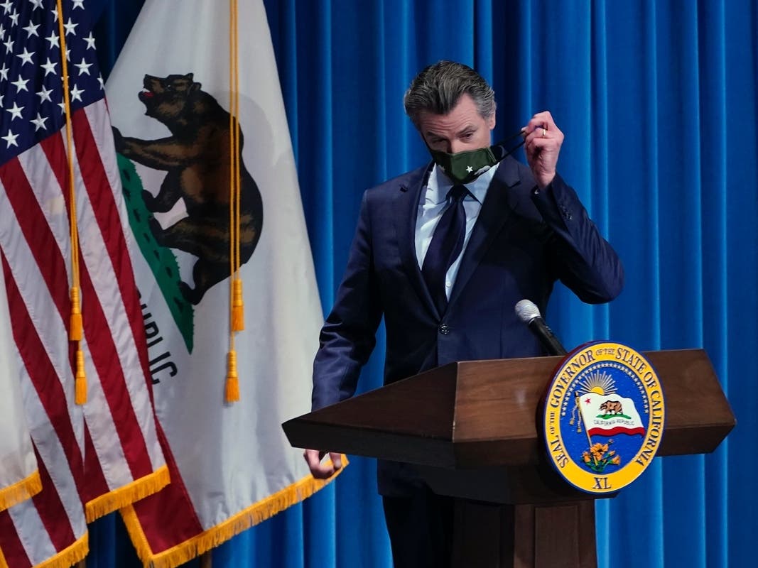 California Gov. Gavin Newsom remove his face mask before presenting his 2021-2022 state budget proposal during a news conference in Sacramento, Calif., Friday, Jan. 8, 2021. 