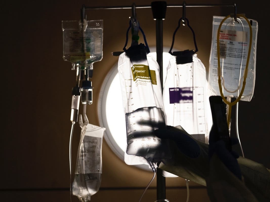 Nurse manager Edgar Ramirez checks on IV fluids while talking to a COVID-19 patient at Providence Holy Cross Medical Center in Los Angeles, Monday, Dec. 13, 2021. 