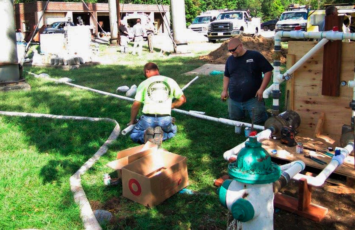 Contractors assemble pipes in 2015 to flush out a fire hydrant beneath the water tower at an IL veterans home.