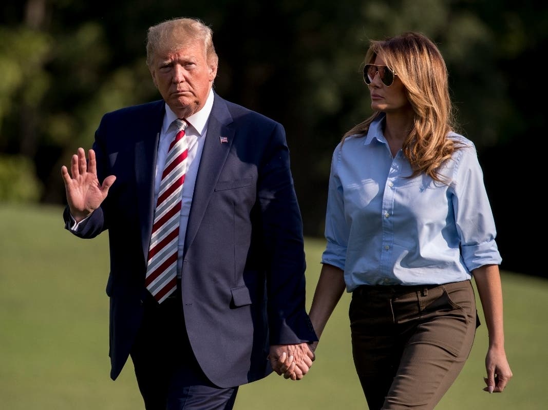 President Donald Trump waves to members of the media as he and first lady Melania Trump walk across the South Lawn of the White House in Washington, Sunday, Aug. 4, 2019, as they return from Bedminster, New Jersey. 