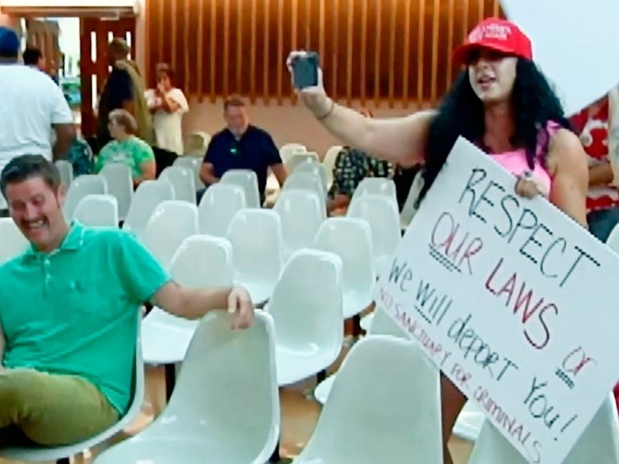 Alex Kack, in the green shirt at left, laughs at a protester during a vote to put a "sanctuary city" initiative on the November ballot during a Tucson City Council Tuesday, Aug. 6. Kack has become known on social media as "#GreenShirtGuy."