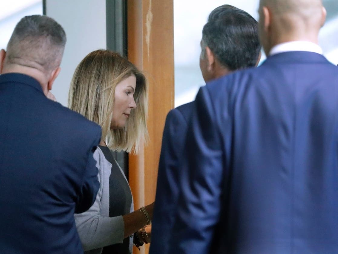 Lori Laughlin, second from left, and her husband Mossimo Giannulli, second from right, enter the back door at federal court in Boston Tuesday.
