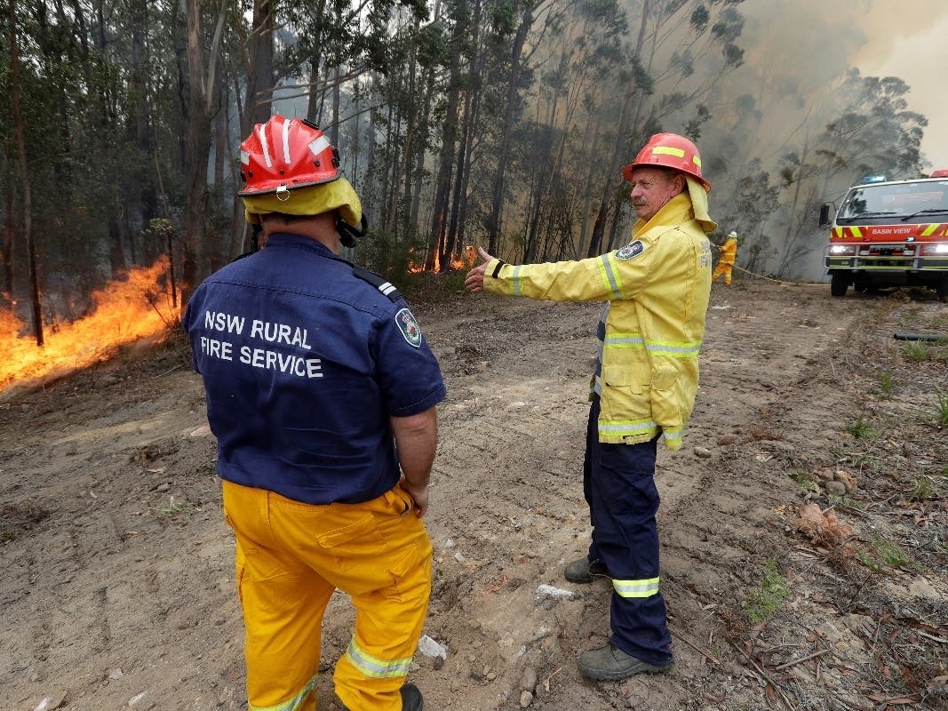 Doug Schutz (right), the Tomerong Rural Fire Service captain, oversees a controlled burn Wednesday near Tomerong, Australia, set in an effort to contain a larger fire nearby. 