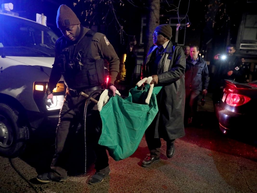 A Chicago police officer and a Chicago Animal Care and Control worker carry a coyote out in a green bag after tranquilizing the animal behind a home Thursday.