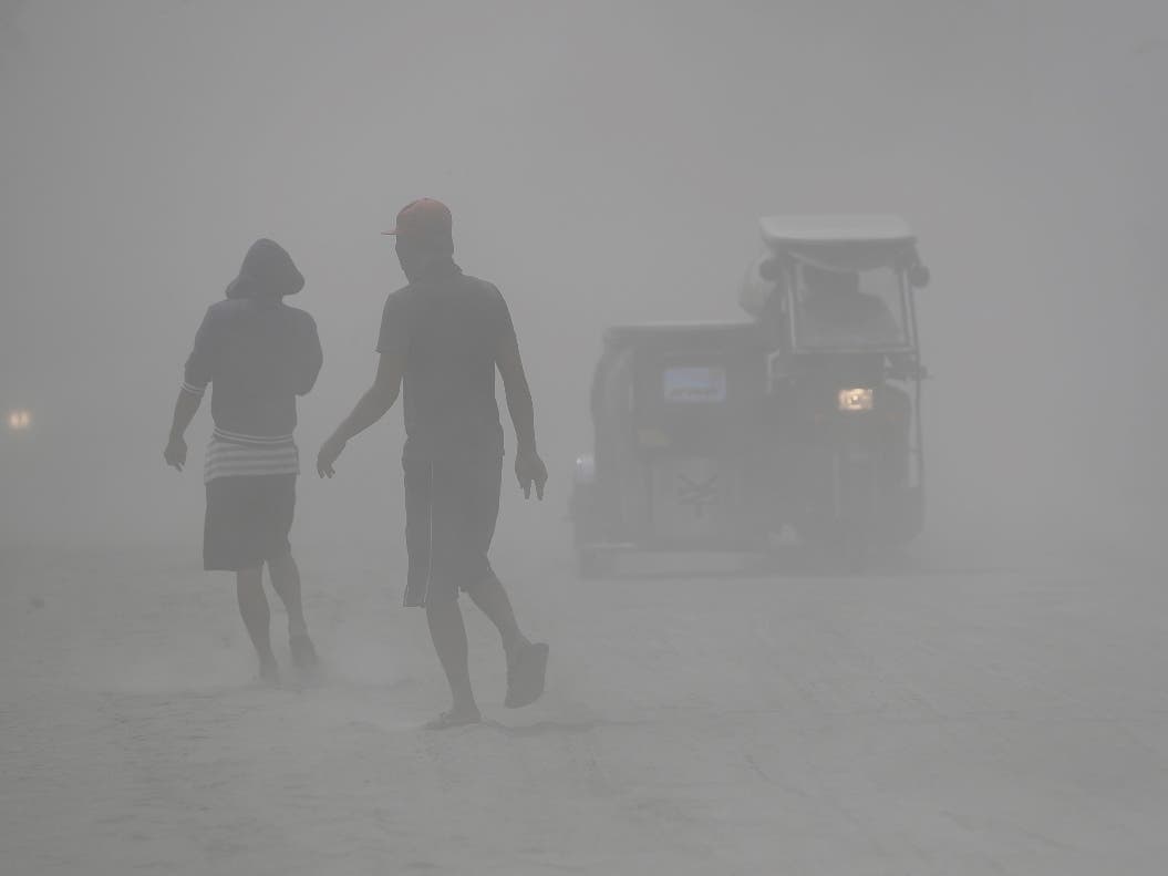 Residents walk in a cloud of ash Monday as Taal volcano continued to spew ash in Tagaytay, Cavite province, south of Manila, Philippines.
