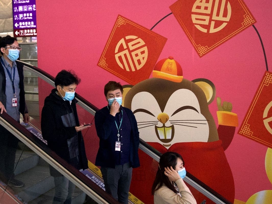 People wear face masks Tuesday as they ride an escalator at the Hong Kong International Airport. Face masks sold out and temperature checks at airports and train stations became the new norm as China strove to control a new coronavirus outbreak.