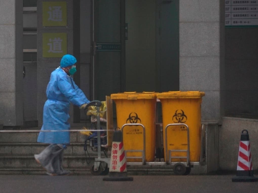 Staff move bio-waste containers Wednesday past the entrance of the Wuhan Medical Treatment Center in Wuhan, China, where some infected with a new virus are being treated.