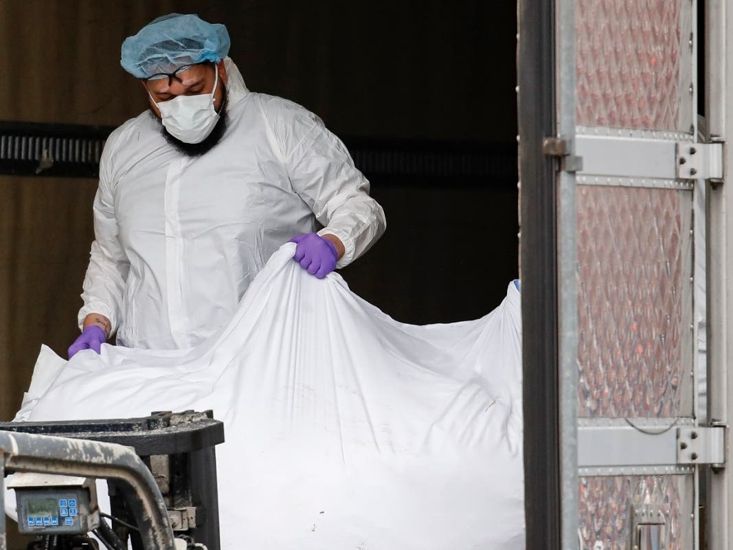 A body wrapped in plastic is loaded onto a refrigerated container truck used as a temporary morgue outside Brooklyn Hospital Center.